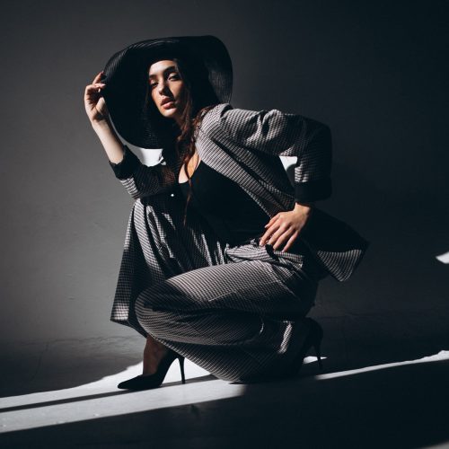 Woman model in a business suit wearing a hat in a studio